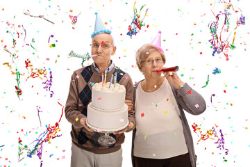 Wall Mural - Senior couple with horns and party hats celebrating birthday