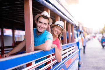 Wall Mural - Traveling Asia. Young handsome man with his girlfriend in traditional thai bus.