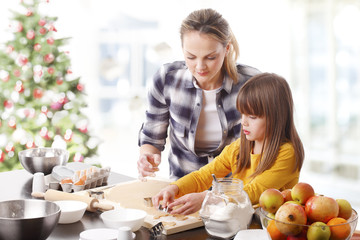 Wall Mural - Christmas timePortrait of happy mother and her cute daughter baking together at home in christmas time. 