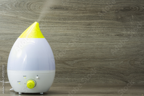 humidificador de ultrasonidos funcionando sobre fondo de madera gris Poster
