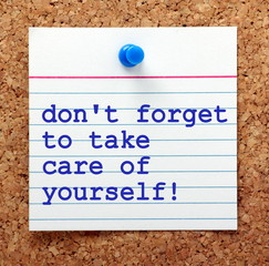 the words don't forget to take care of yourself on a note card pinned to a cork notice board as a re