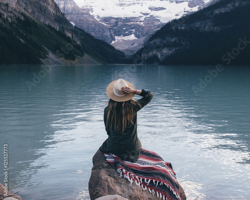 Fotomural Rear view of woman sitting on rock and looking Lake Louise, Alberta, Canada