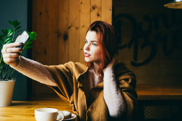 beautiful young woman taking a selfie with a coffee in a cafe