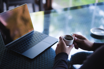 Fresh coffee for great ideas. Top view man working on laptop and holding cup of coffe while sitting at cafe