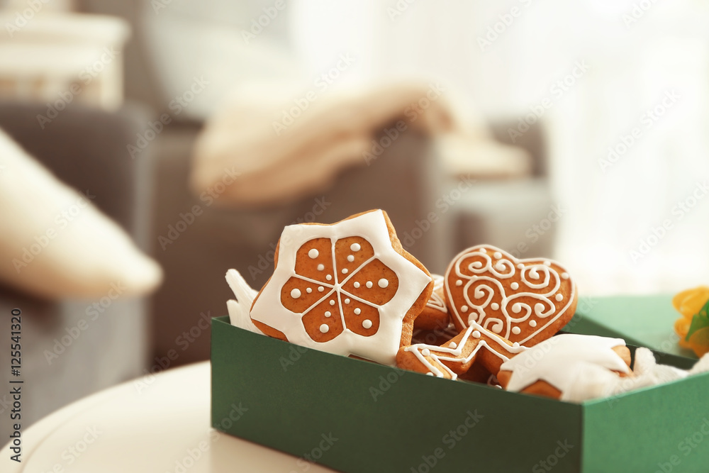 Box with tasty gingerbread cookies on blurred background, close up view