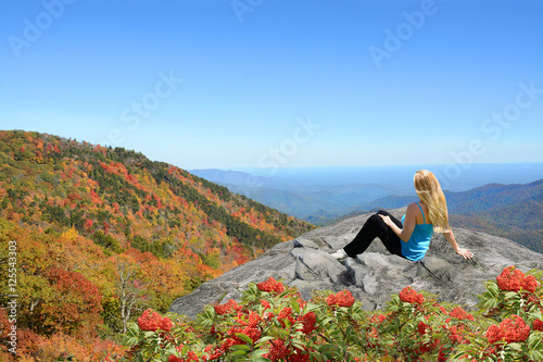 Fotografie, Obraz Young woman siting and relaxing on the top of the mountain