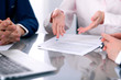 © rogerphoto - Group of business people and lawyers discussing contract papers sitting at the table, close up