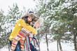 © scharfsinn86 - Loving couple in the winter park. Man and woman dressed in sweaters and scarves, winter hats. Snowfall in the forest, holidays, travel.