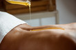 © Cookie Studio - Honey pouring on girl's naked back in spa salon.