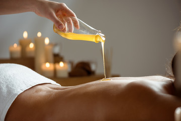 Honey pouring on girl's naked back in spa salon.