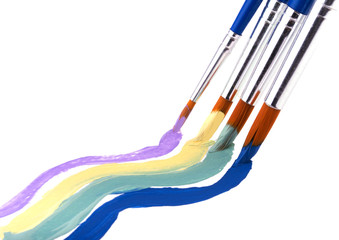 Four paint brushes with pleasing pastel color paint, on white background