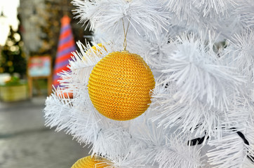 Yellow Christmas toy on a white fluffy tree. Christmas holidays and New Year's toys.