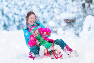 Wall Mural - Mother and child sledding in a snowy park