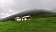 two small huts with foggy mountain on background, winter, ranny season, weather, green field
