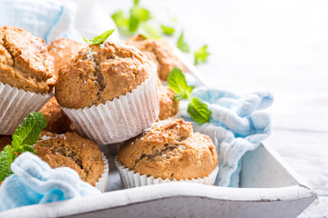 Delicious homemade coconut cinnamon muffins and mint leafs on old white tray. Healthy food concept with copy space.