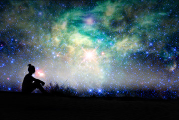Silhouette of a woman sitting outside, starry night background