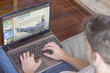 © GENETTICA - Pay per view concept: Young man at home viewing video on demand web on laptop.
