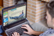 © GENETTICA - Close-up top view of young man at home using laptop with video on demand website on the screen. All screen graphics are made up.