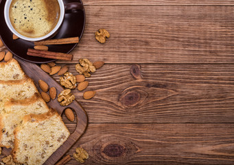 Homemade nut cake with cup of coffe on wooden background.
