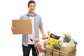 Poster - Young man with shopping cart and blank cardboard sign