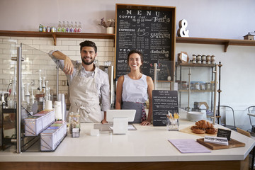 Wall Mural - Couple ready to serve behind the counter of a coffee shop