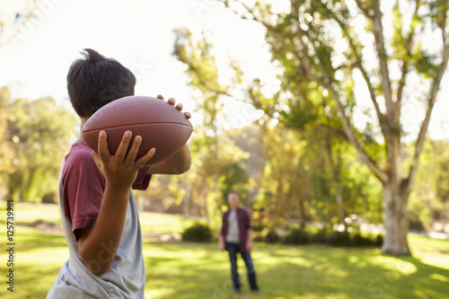 Fotomural Young boy throwing ball to dad in park, focus on foreground