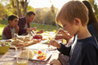 © Monkey Business - Young boy eating at a picnic table in a park