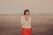 Молодая красивая женщина с короткой стрижкой в оранжевой юбке и белом свитере стоит в поле 