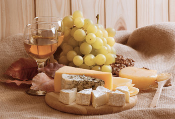 Wall Mural - Various types of cheese served with grapes, walnuts, honey and w