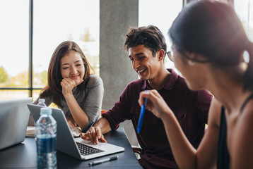 Young students studying together using laptop