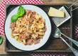Italian pasta dinner. Homemade Tagliatelle Bolognese with Parmesan cheese and fresh basil in wooden tray over rustic wooden background, top view