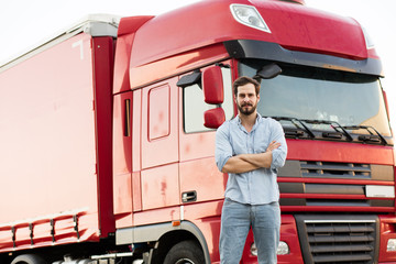 masculine truck driver in jeans with his truck behind