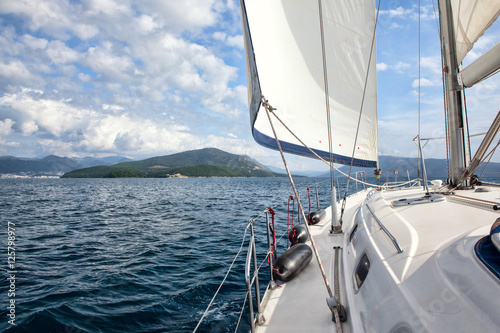 Fototapeta na wymiar Front part of a sailboat, set on full sails to the sea