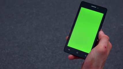 young man works on smartphone on the street - green screen - detail