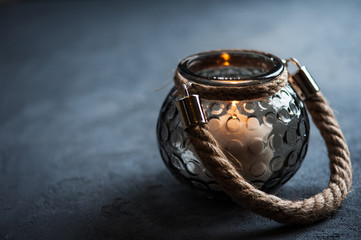 Lantern with a lit candle on concrete background