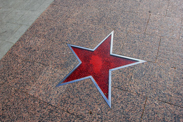 granite paving of the sidewalk with big red glass star with meta