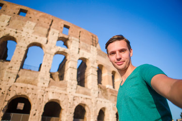 Young man taking selfie portrait in front of Colosseum in Rome, Italy