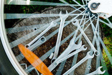 Bicycle repair. Tools, instrument for repairing bike on the wooden background with spokes of a wheel in the foreground. Close up.