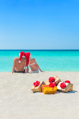 Canvas Print - Golgen gifts and couple in Christmas Santa hats at beach