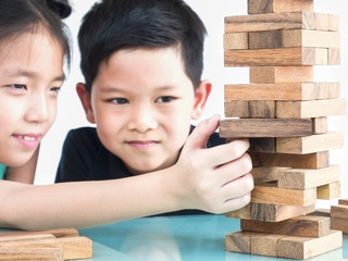 Wall Mural - Children are playing a wood blocks tower game for practicing their physical and mental skill