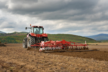 Fototapete - Farmer in tractor preparing land with seedbed cultivator
