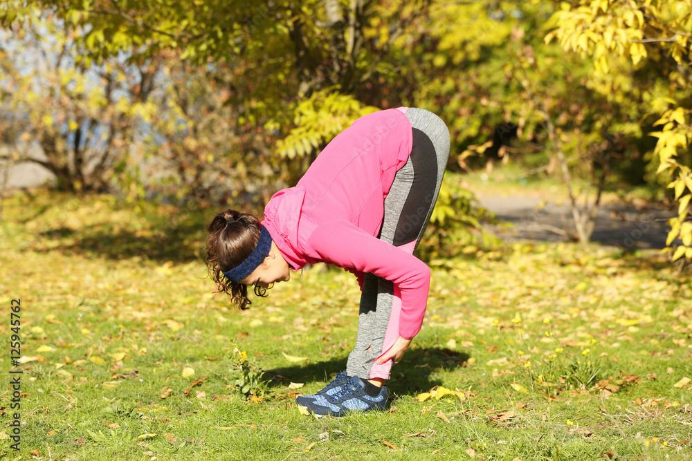 Sporty young woman training in autumn park