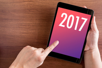 Poster - Hand touch tablet with 2017 year number on screen on wood table,