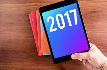 Poster - Hand holdling tablet with 2017 year number on screen over notebo
