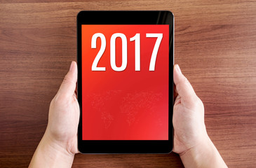 Poster - Hand holdling tablet with 2017 year number on screen on wood tab