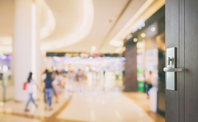 opened wooden door to department store with people shopping as background.