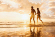 © NicoElNino - Happy cheerful couple running to the sea, water splashes, sunset