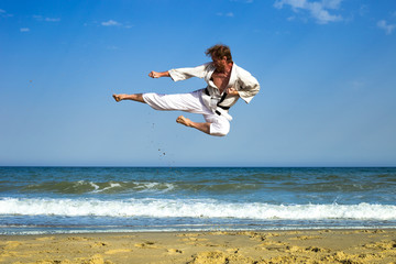 Adult man practicing a kata and kicks on the beach