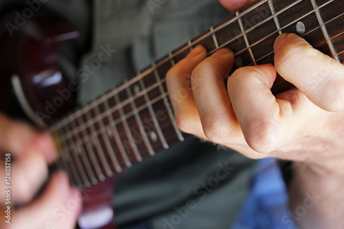 Fotografie, Obraz Closeup of a guitarist's hand forming a chord on the fretboard.