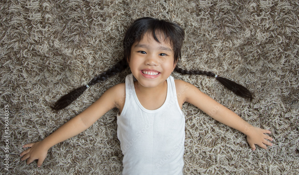 smiling cute little girl lying on the carpet Stock Photo | Adobe Stock